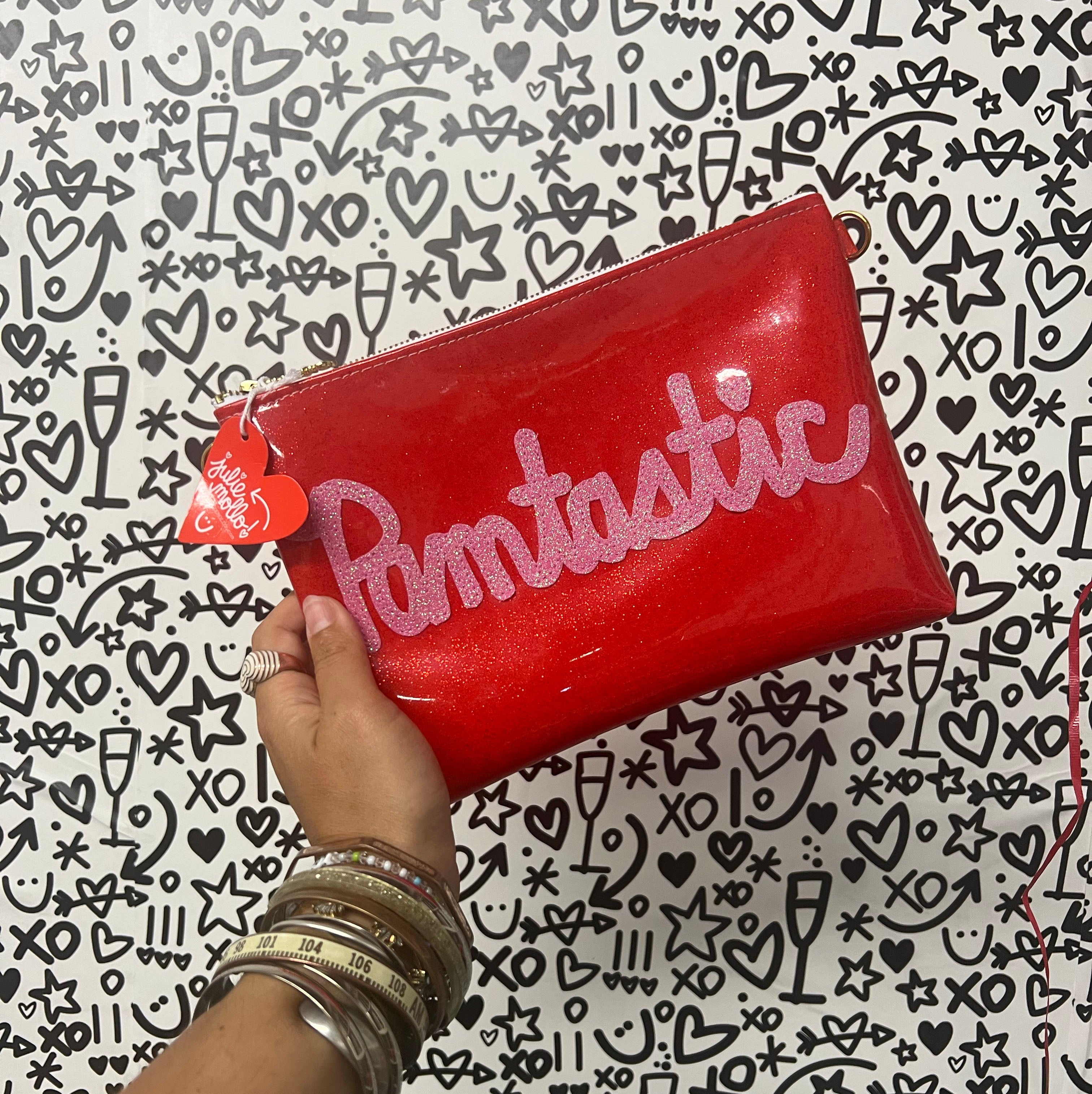 Customizable crossbody bag that features "Pamtastic" name applique in pink sparkly canvas on a red glitter infused vinyl. Crossbody strap is a clear acrylic chain. 