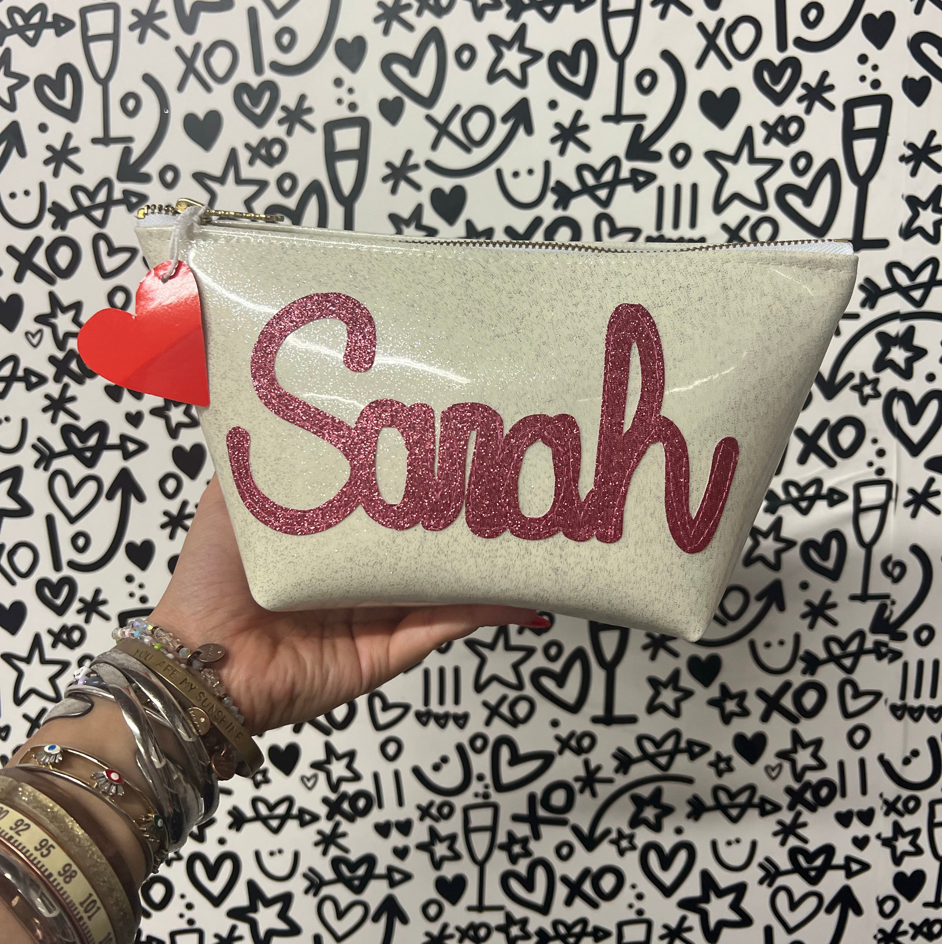 Cute and custom white glitter infused vinyl pouch with a pink glitter "sarah" applique sewn on the front.