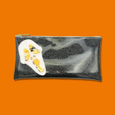 Glitter infused black vinyl bag with a white 'Ghostface' applique with orange confetti weed leaves for the eyes, nose, and mouth. Clutch is featured on a bright orange background. 