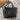black glittery vinyl tote bag with the letters "jmng" in sparkly black letters on the front. The bag features a removable shoulder strap with a fun, doodle-inspired pattern of stars, hearts, and shapes. Bag is held in front of cute doodle print wall. 