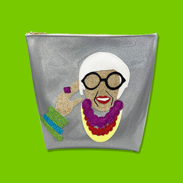 Colorful glitter canvas portrait of Iris Apfel on a glitter infused silver vinyl bag. Bag has a Julie Mollo custom XOXO zipper pull on the top.