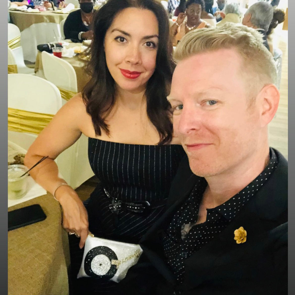 Woman holding a Sparkly silver, black, and gold turntable sewn onto a silver glitter infused vinyl clutch. On the top of the clutch is a cute XOXO zipper that is custom to Julie Mollo!.
